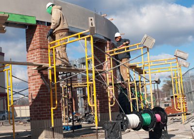 Construction electricians wiring radius atop brick columns