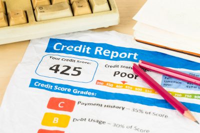 Poor credit score report on wrinkled paper with pen and keyboard