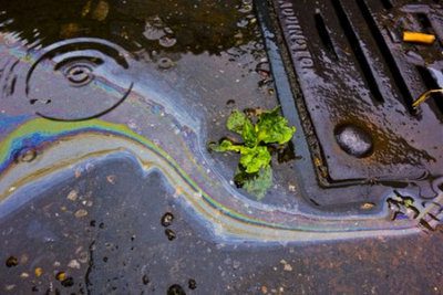 Oil petrol rainbow leak running down a drain