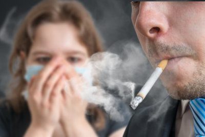 man smoking while girl is covering her nose