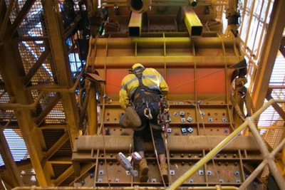 Male rope access industry worker wearing safety harness